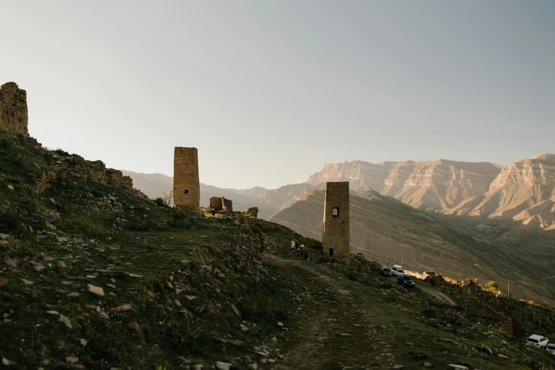 two rock buildings sit on the side of a hill