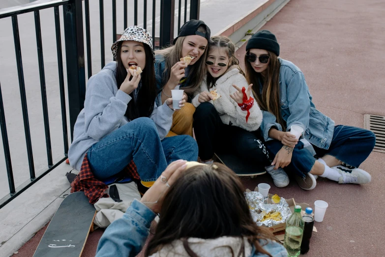 three girls and their mom eating while sitting on the ground