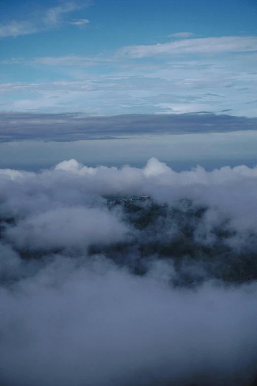 an airplane flying high above the clouds on top of a mountain