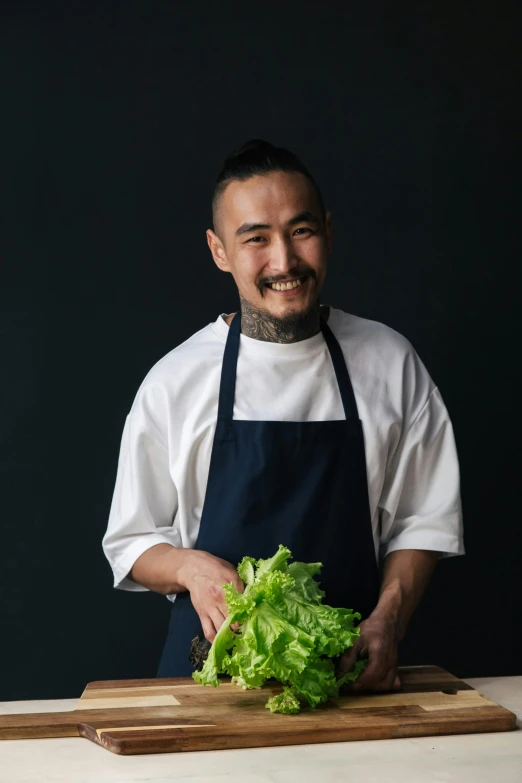 a man in an apron smiling and preparing a salad