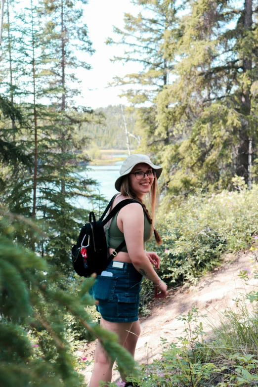 a woman standing by some water and trees