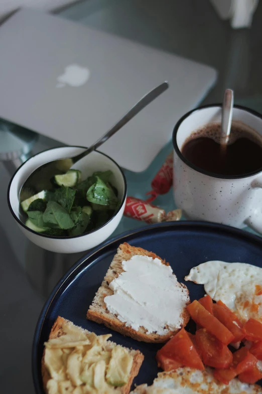 an apple laptop is next to a plate of breakfast foods