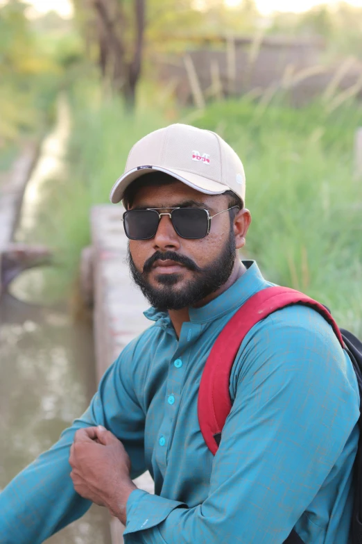 a man wearing sunglasses and a blue shirt looks at the camera