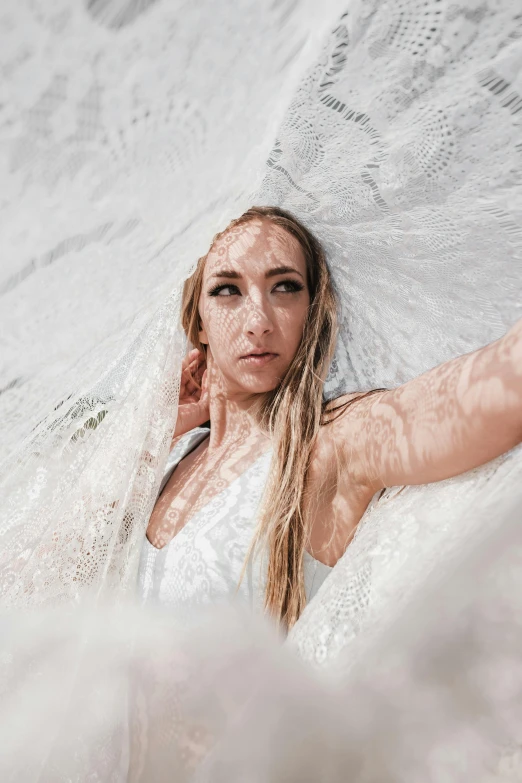 an attractive blond woman lies in a white net