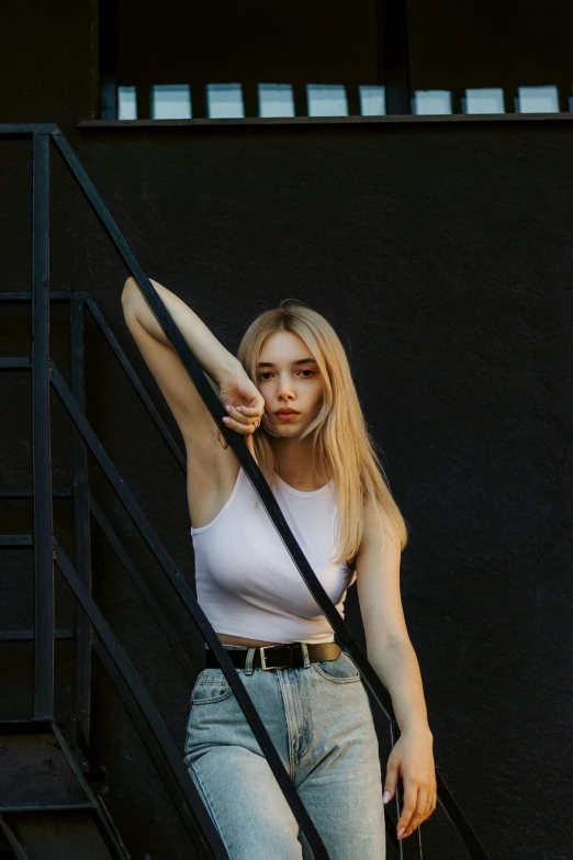 a beautiful young blond lady leaning against some stairs