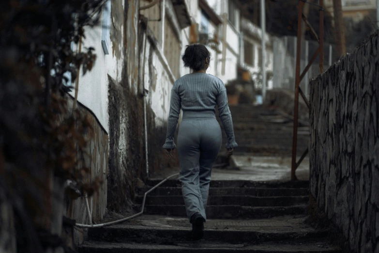 woman walking down the street in high - rise alley