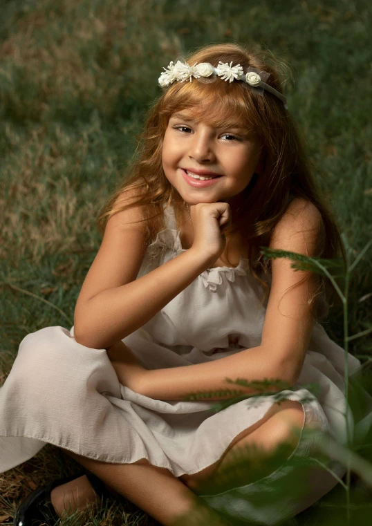 a girl is sitting in the grass posing for a picture