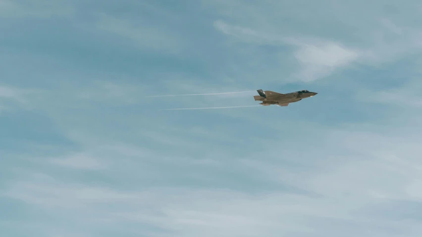 a fighter jet flying through a blue cloudy sky