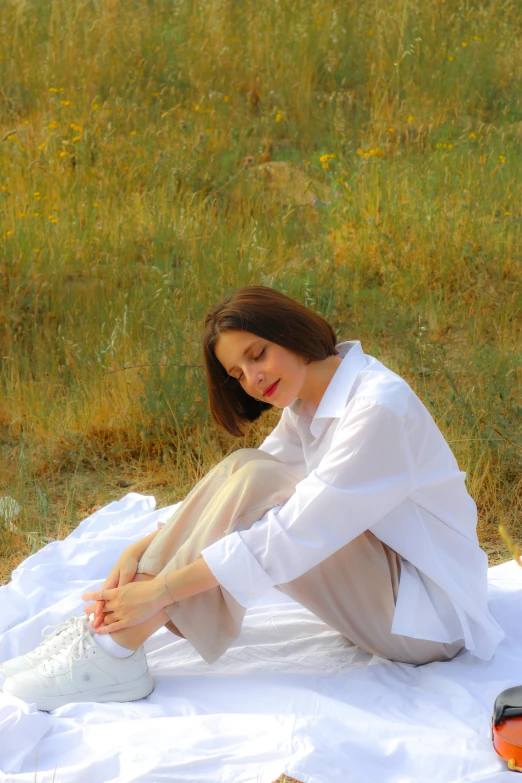 a woman that is sitting on a blanket outside