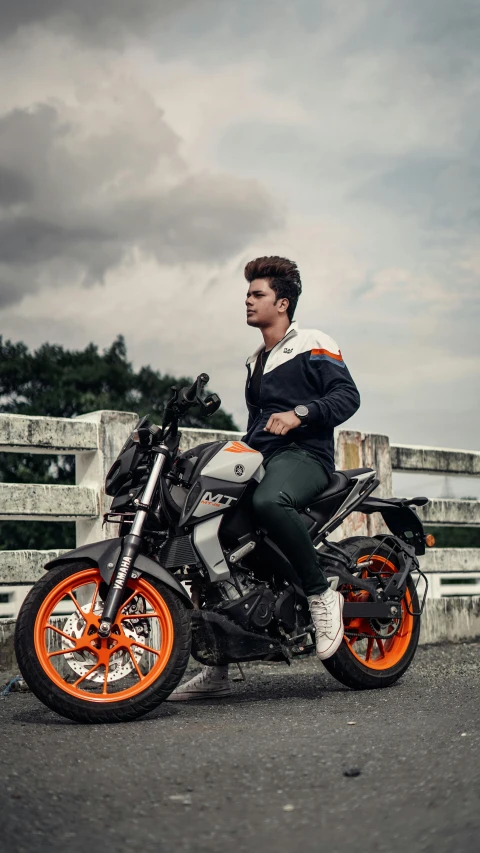 young man riding orange black and white motorcycle