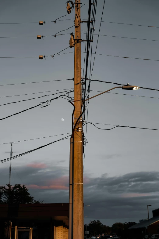 multiple electric wires and street lights in front of a cloudy sky