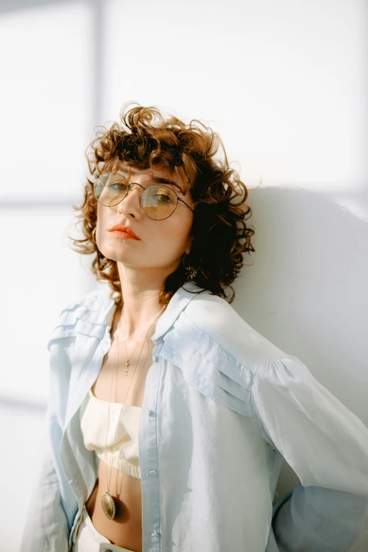 woman with short hair wearing an eye patch sitting on a white wall