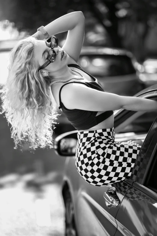 a woman standing on top of a car next to a black car