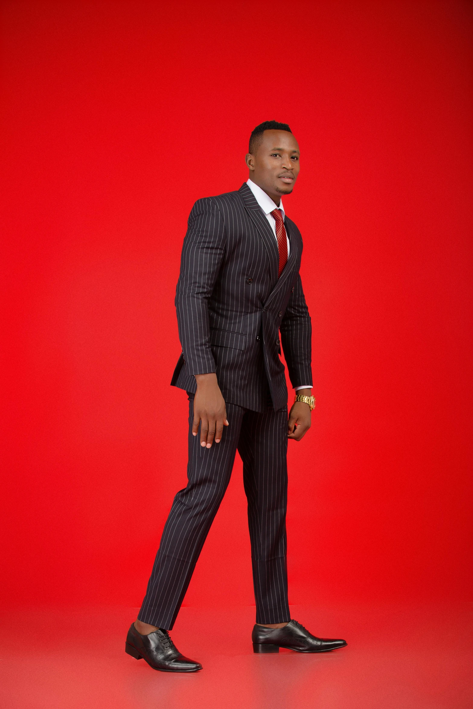 a man in a suit and tie walking against a red background