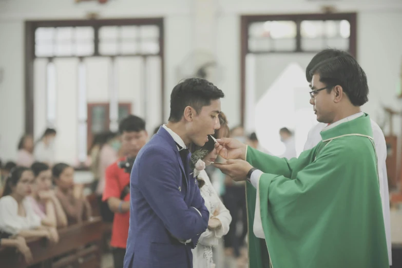 a man in green priest clothes feeding a child