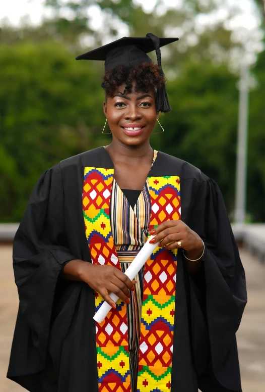 a female in a colorful graduation gown holding a white pen