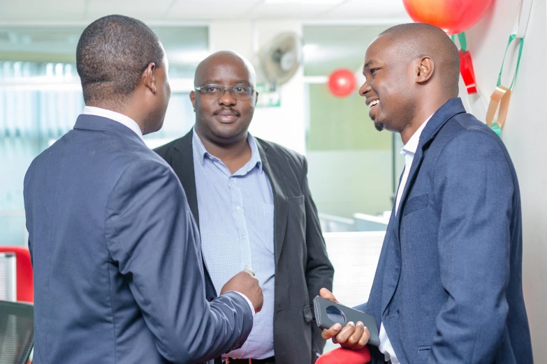 three men talking to each other in a room