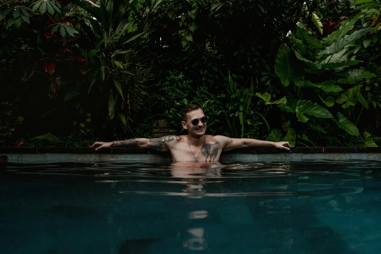 a man floating in the pool surrounded by jungle