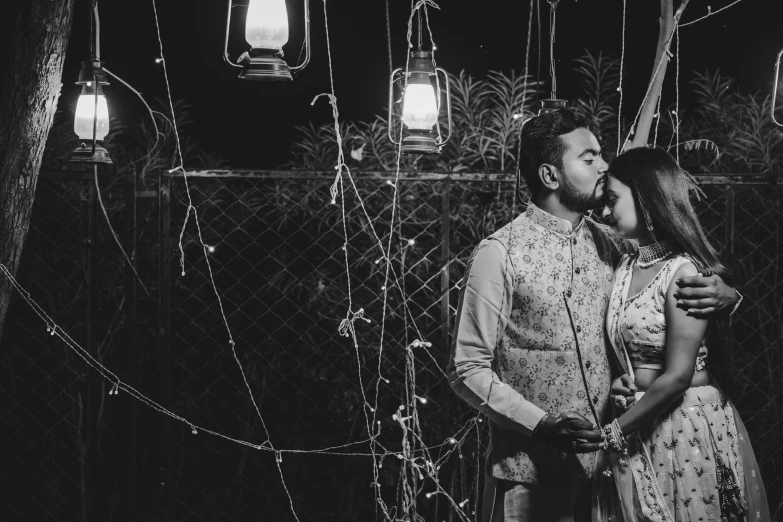 couple poses in front of decorative lights and hanging lanterns