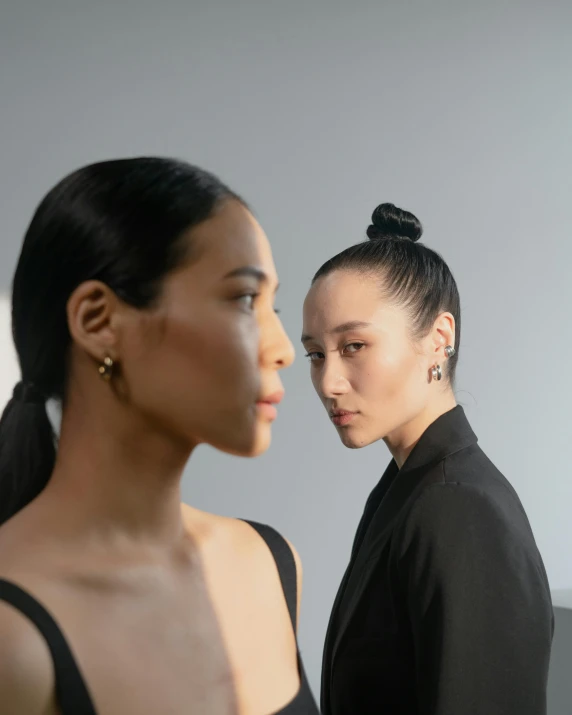 two women wearing earrings are standing side by side