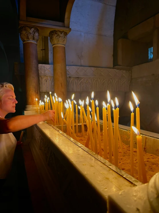 man in church with yellow lighted candles on a bench