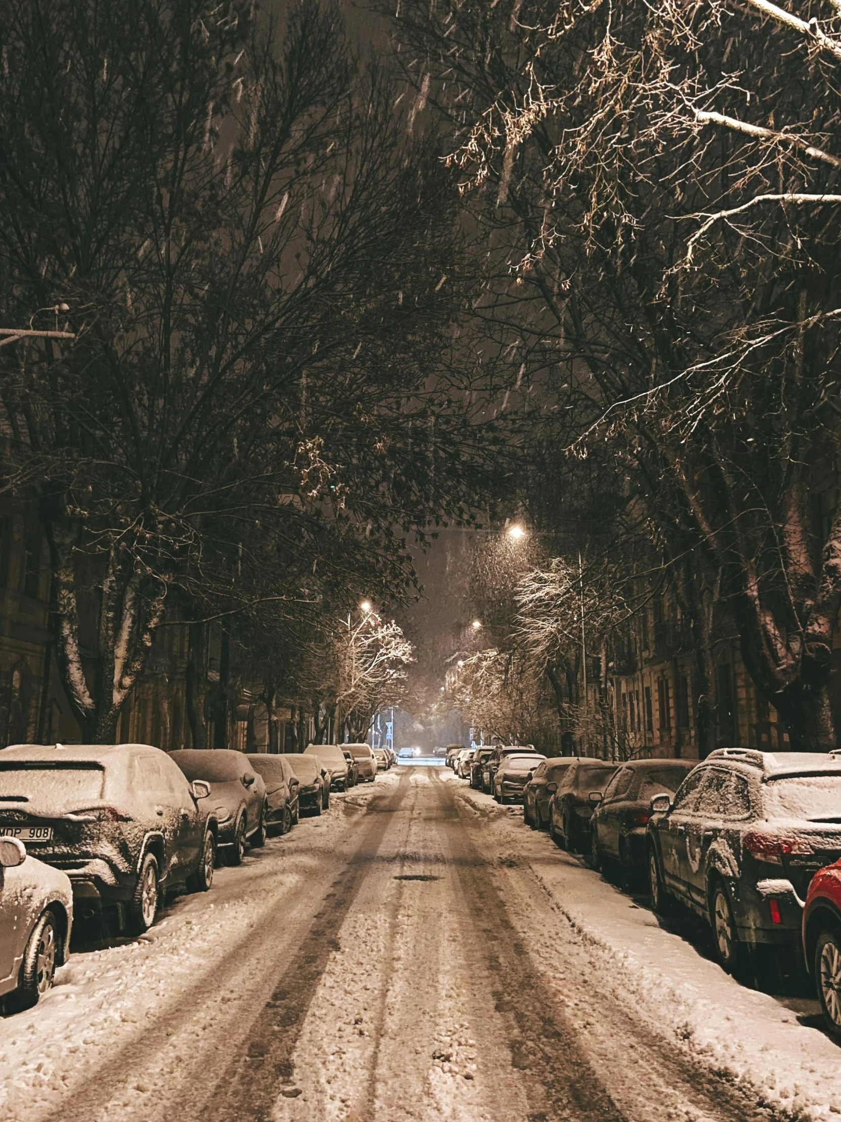 a long snowy street with lots of cars parked on it