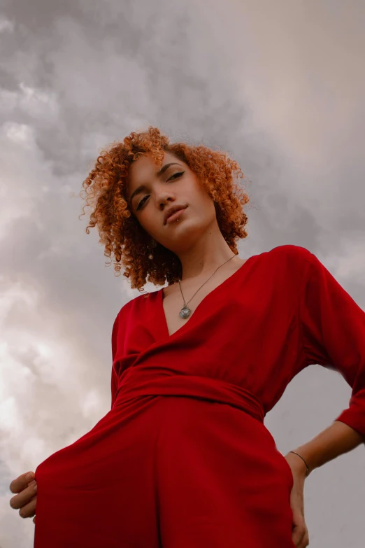 a red haired woman in a red dress is posing for the camera