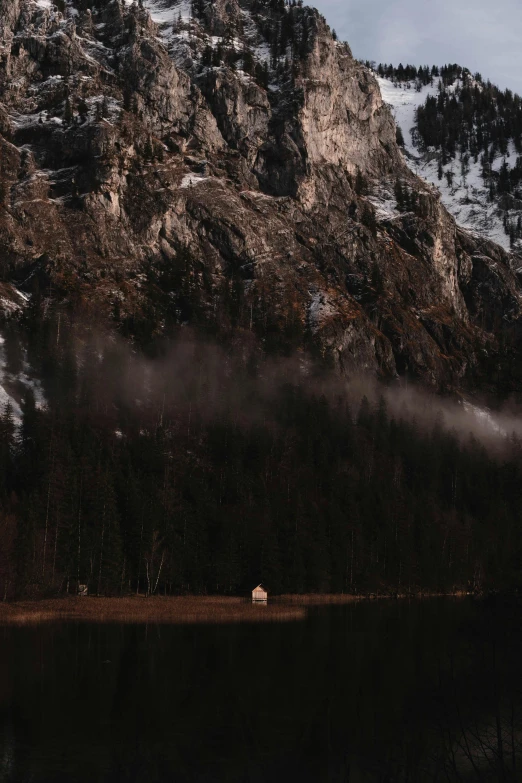 a small house in the mountains near a body of water