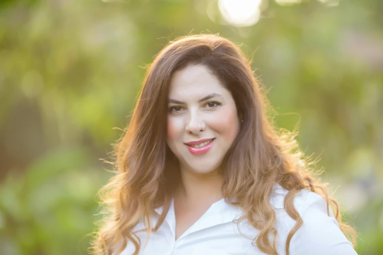 a woman wearing white shirt standing in front of trees