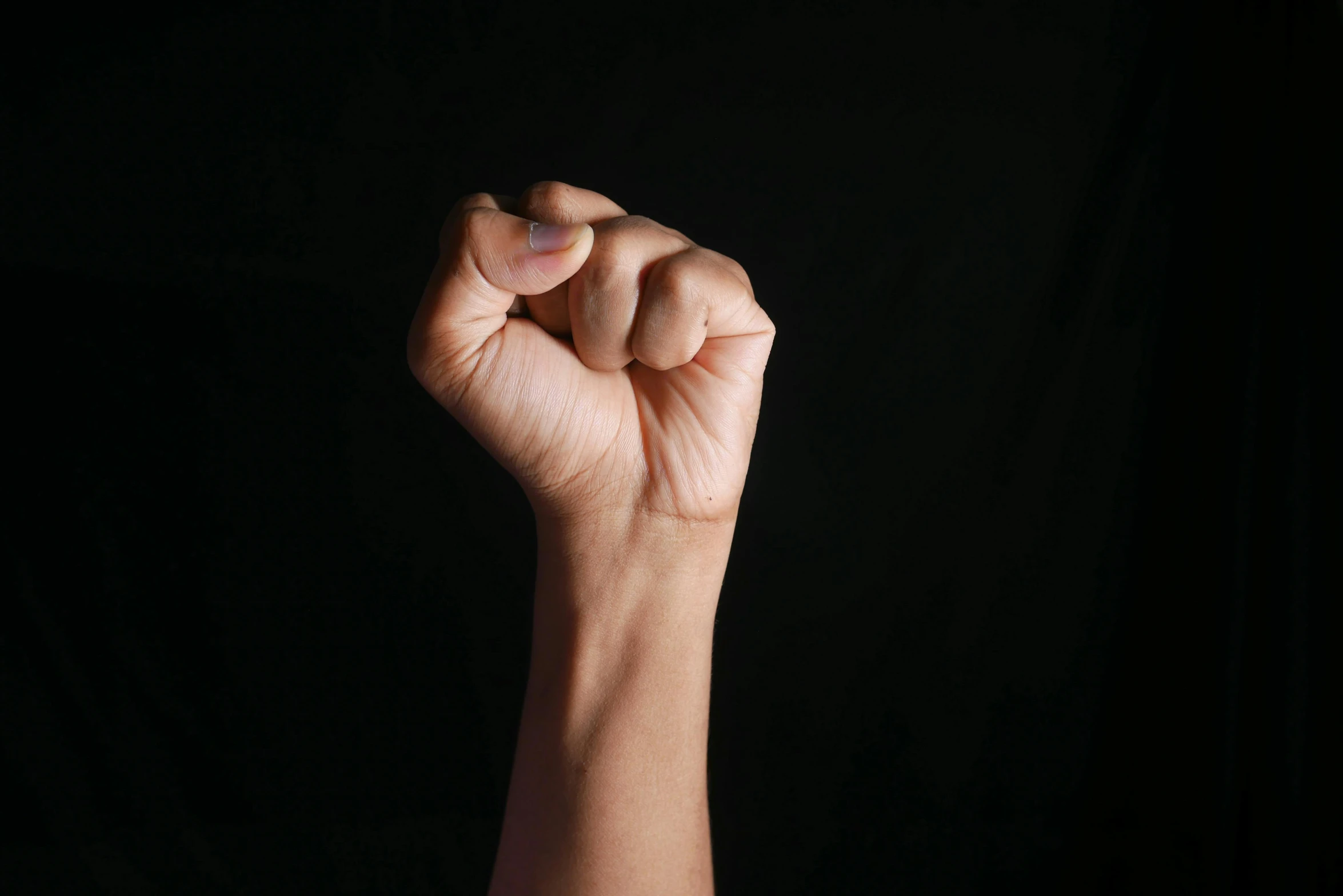 a person holding their fist in front of a black background