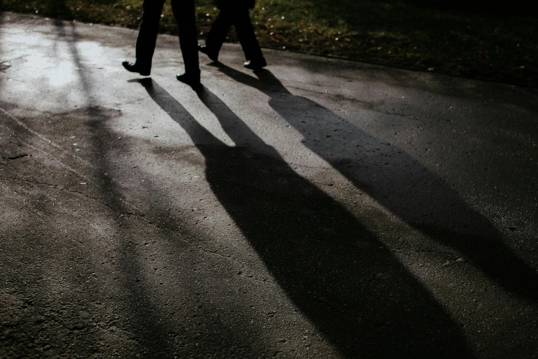 shadows of people walking on a path in the dark