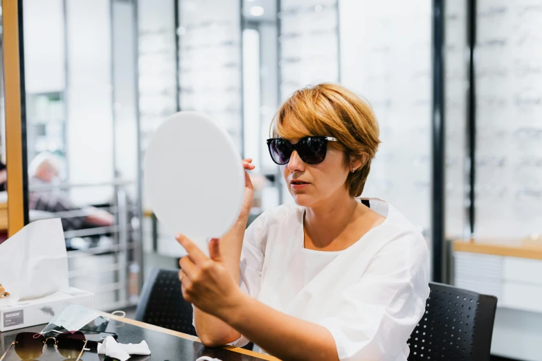 woman sitting at table looking through eyeglasses