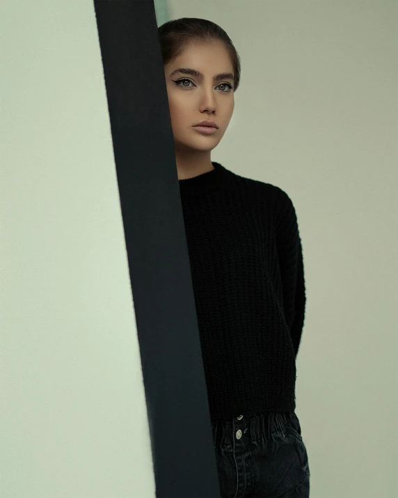 a woman wearing black standing against a wall