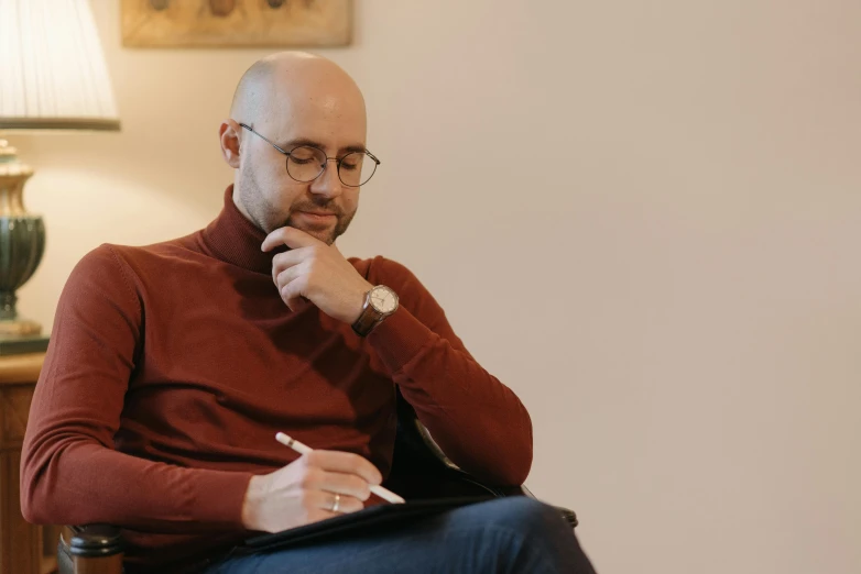 a man sitting in a chair holding his pencil in his mouth