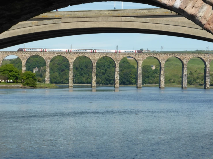 a bridge with multiple arches and a train on it above the water