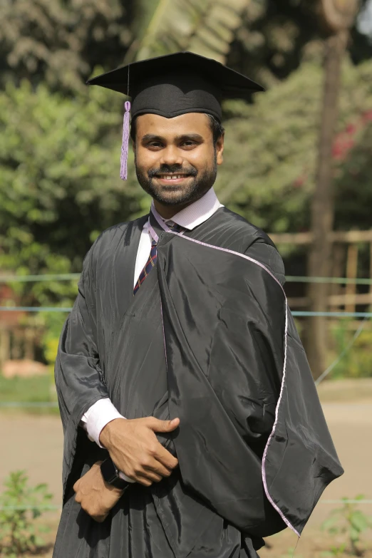 a man in cap and gown posing for the camera