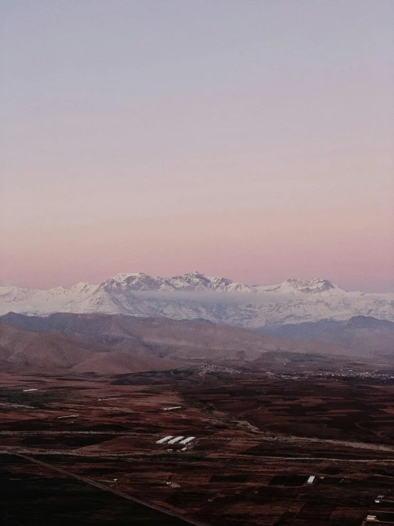 a snow - capped mountain range in the distance, while the air is mostly pink