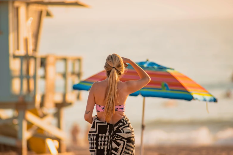 a blonde female on the beach is wearing a colorful bikini