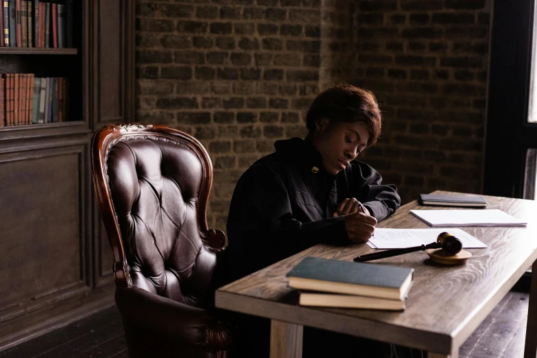 a person sitting in a chair writing on a book