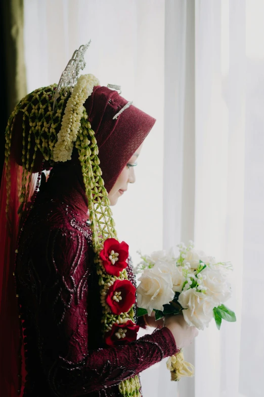 a woman in a red veil and a veil holding flowers