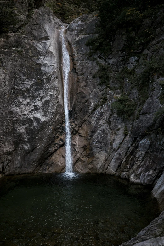 a small pool and waterfall at the top of a cliff