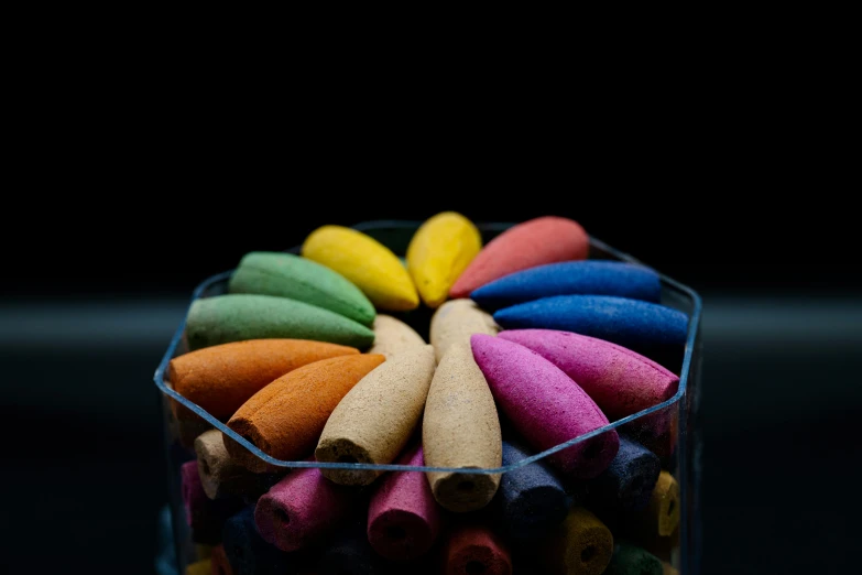 colored crayons in a glass container on a black background