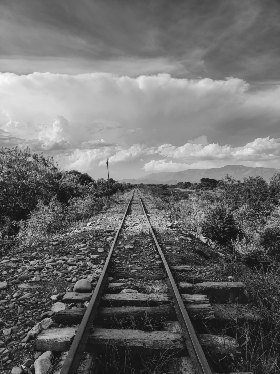 an empty railroad track with a sky in the background