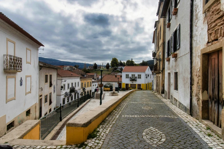 a cobblestone street with white and tan buildings