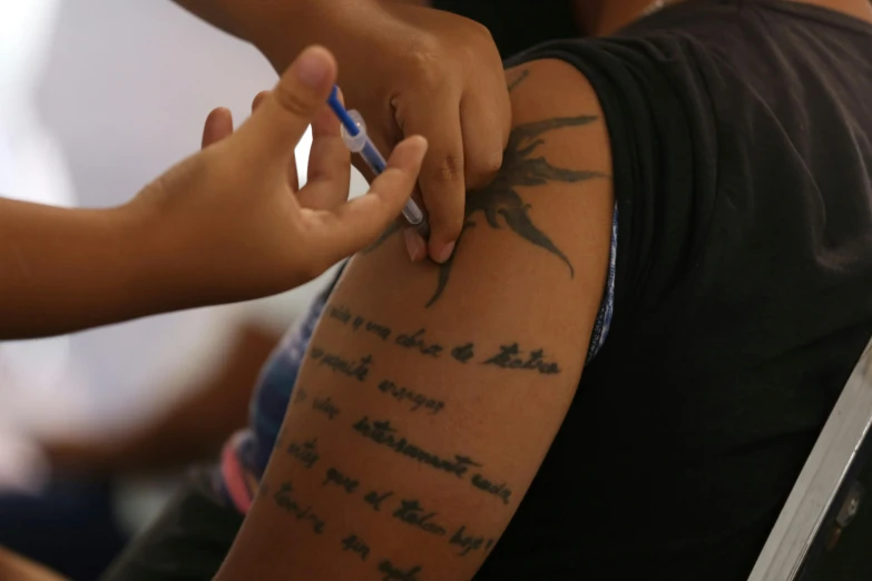 a person with tattoos on her arm writing on a piece of paper