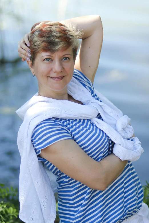 a smiling woman leaning on the edge of a body of water