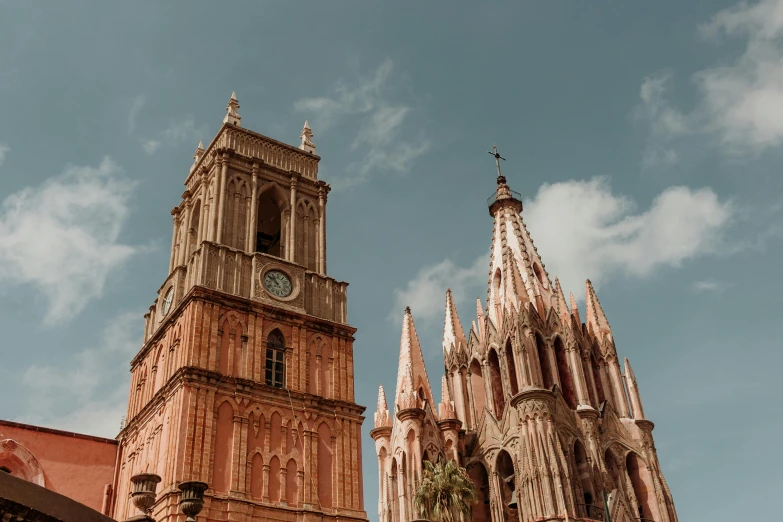 large brown building with steeple and clocks against sky