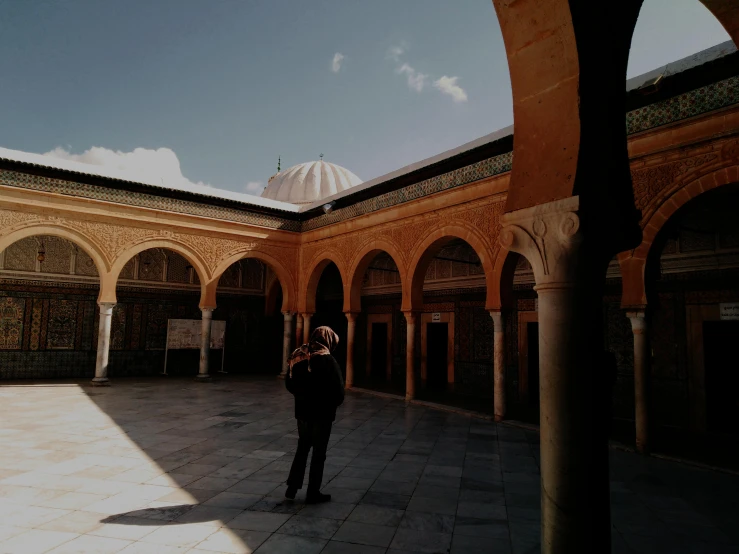 a person is standing under a building with arches