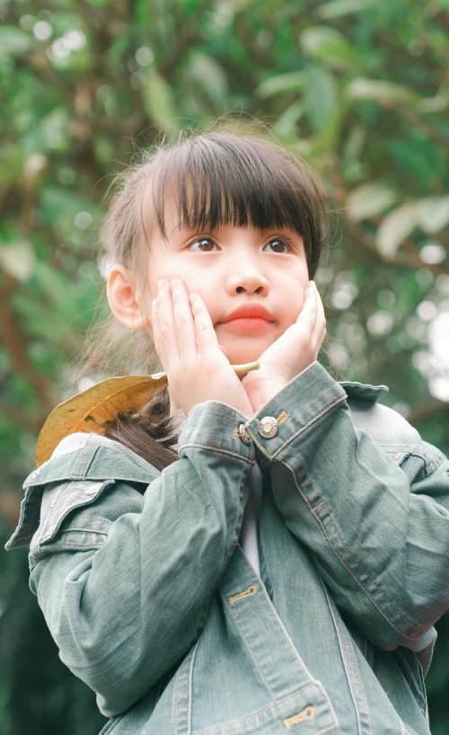 a little girl standing in front of a tree