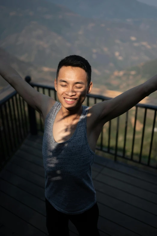 a man on a deck holding his arms up and smiling